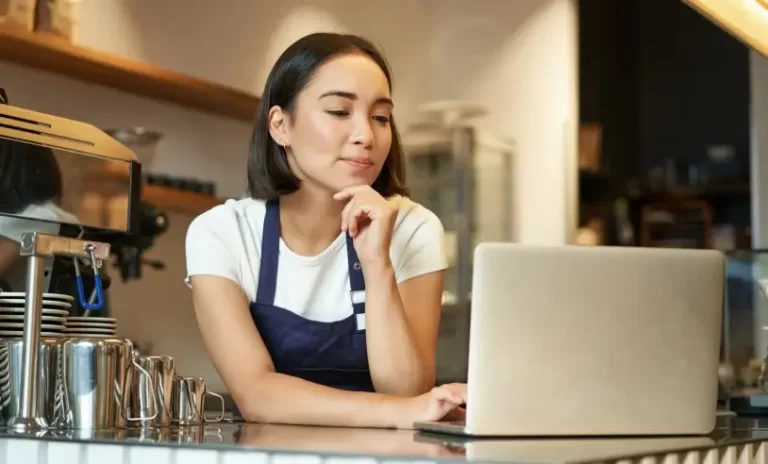 retrato-de-uma-sorridente-barista-coreana-em-uma-cafeteria-parada-no-balcao-com-um-laptop-sorrindo-e-scaled_p28099_cover_image_resized